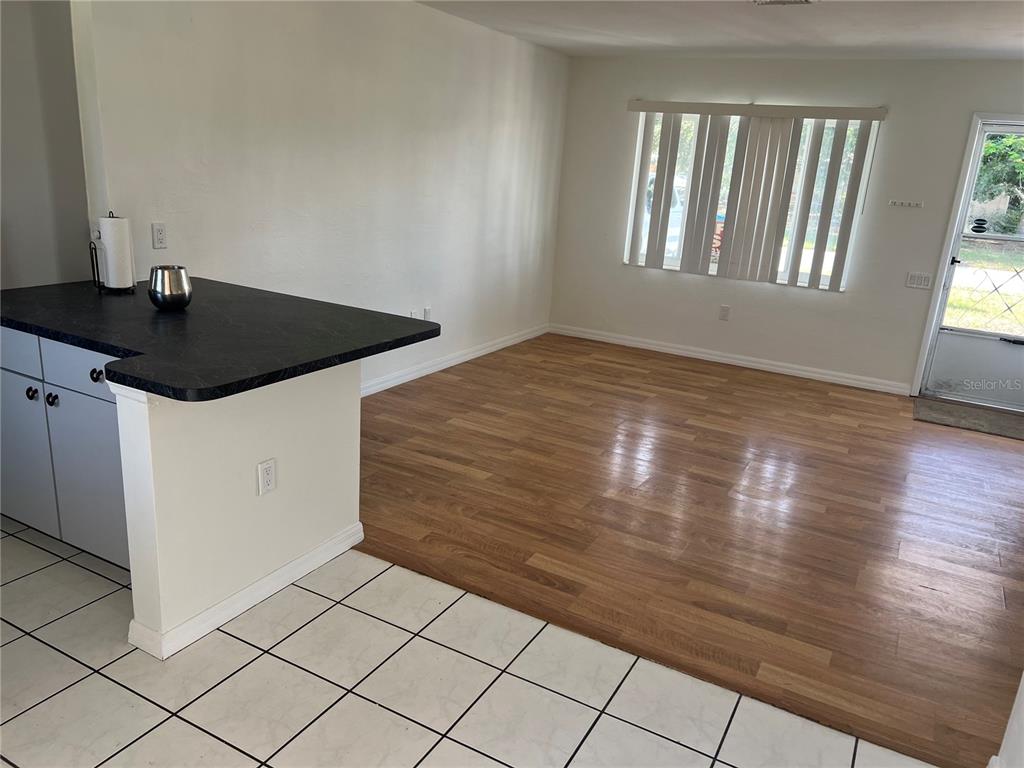 A kitchen features white cabinets, dark countertops, a double sink, and white tile flooring — 10934 FREEDOM BOULEVARD, SEMINOLE, FL