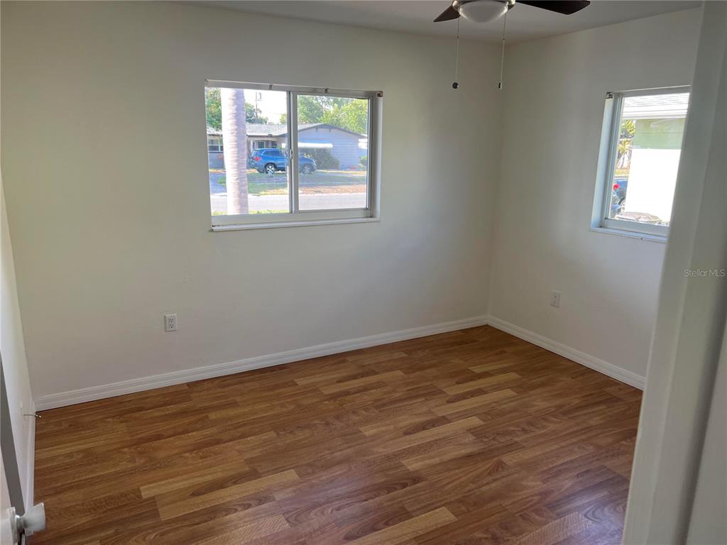 A kitchen with a black countertop overlooks a living area with wood-look flooring — 10934 FREEDOM BOULEVARD, SEMINOLE, FL