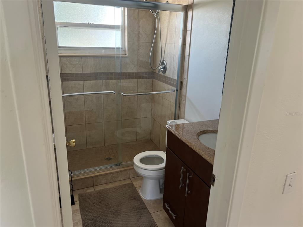 An empty bedroom features light-colored walls, wood-look flooring, two windows, and a ceiling fan — 10934 FREEDOM BOULEVARD, SEMINOLE, FL
