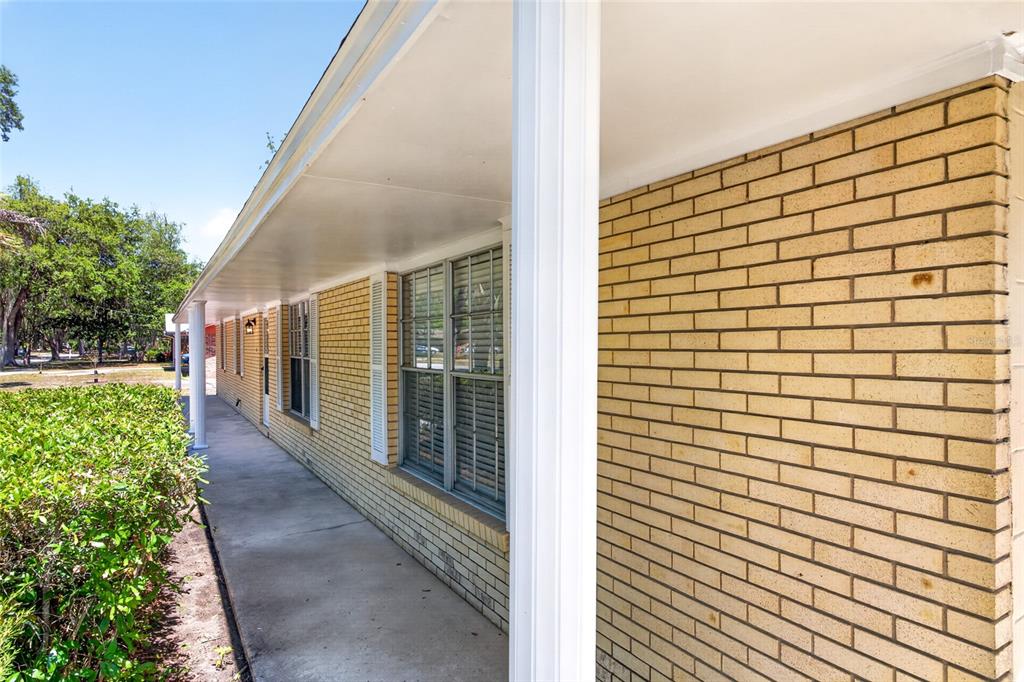 A concrete walkway runs along the side of a house with light-colored brick walls — 3907 NW 21ST STREET, GAINESVILLE, FL