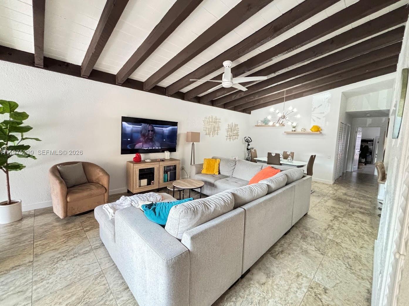 A living room features a vaulted ceiling with exposed dark wood beams and tile flooring — 6937 SW 115th Pl # C37, Miami FL 33173, MIAMI, FL