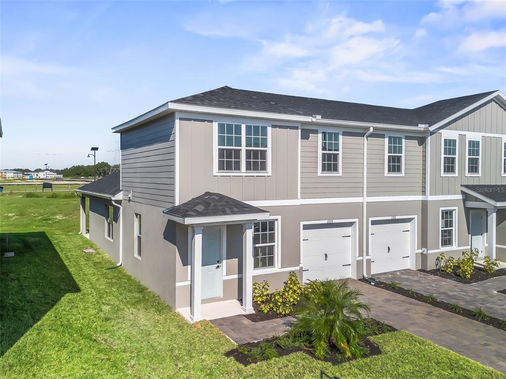 An exterior view of a two-story townhouse with a gray facade and a paved driveway — 1205 PORT BLUE WAY, LADY LAKE, FL