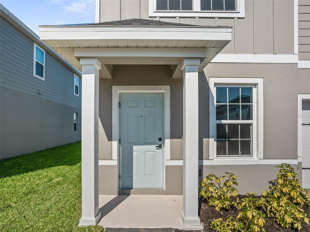 A light blue front door sits under a covered porch with white columns — 1205 PORT BLUE WAY, LADY LAKE, FL