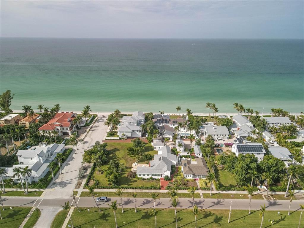 An aerial view shows a coastal neighborhood with several houses near a turquoise ocean beach — 231 GILCHRIST AVENUE, BOCA GRANDE, FL
