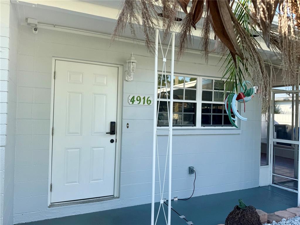 The exterior of a light blue house features a white front door and a window — 4916 ELDORADO DRIVE, TAMPA, FL