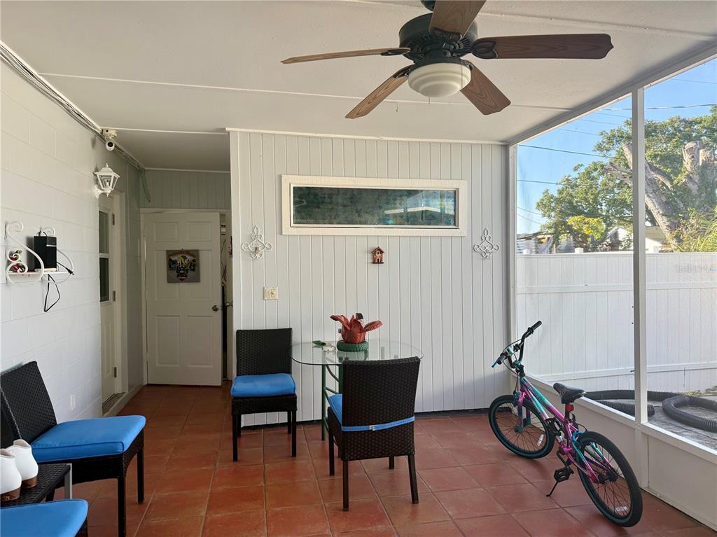 A screened-in porch with tile flooring, a ceiling fan, a glass table, and a bicycle — 4916 ELDORADO DRIVE, TAMPA, FL