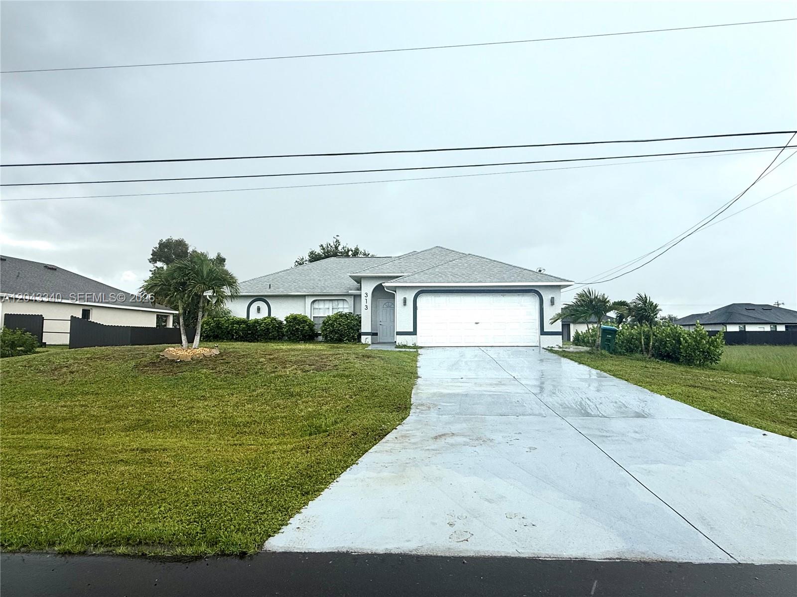 A single-story house with a white garage door, gray roof, and a paved driveway — 313 NW 16 PL, Cape Coral FL 33993, CAPE CORAL, FL