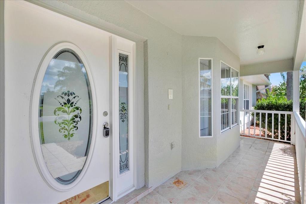 A covered porch with tiled flooring leads to a white front door with decorative glass — 112 AZALEA DRIVE, DAVENPORT, FL