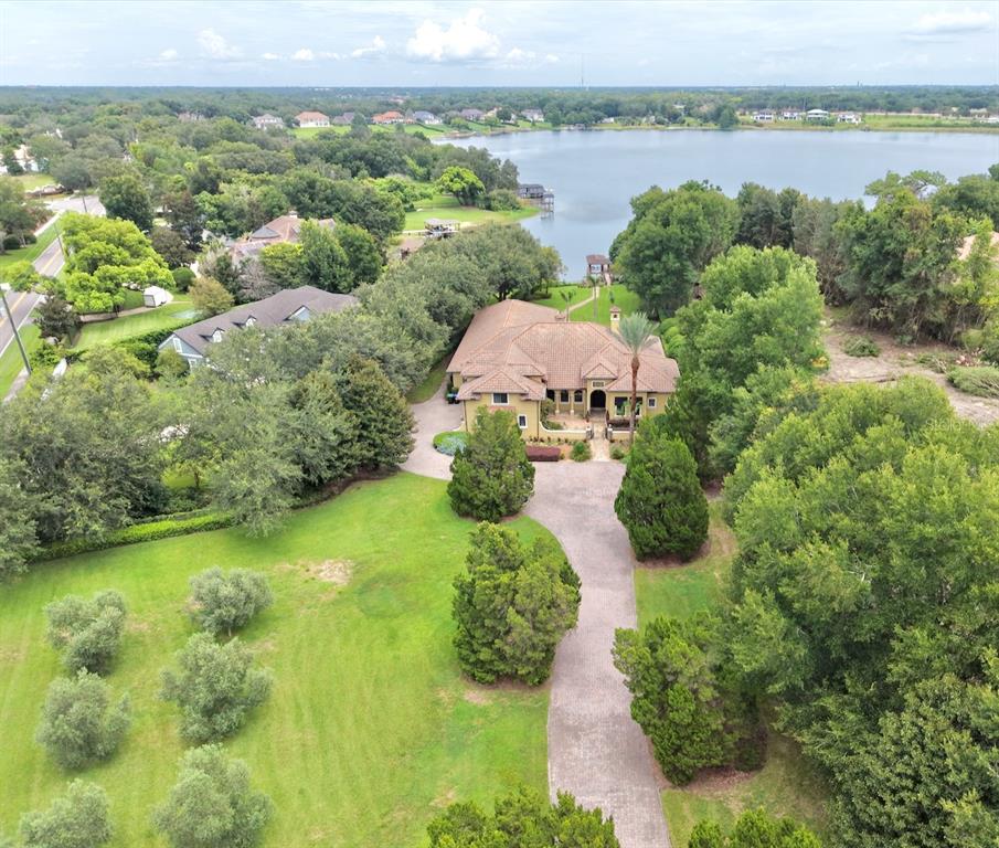 An aerial view shows a large house with a tile roof, driveway, and surrounding trees — 9679 WESTOVER ROBERTS RD, WINDERMERE, FL