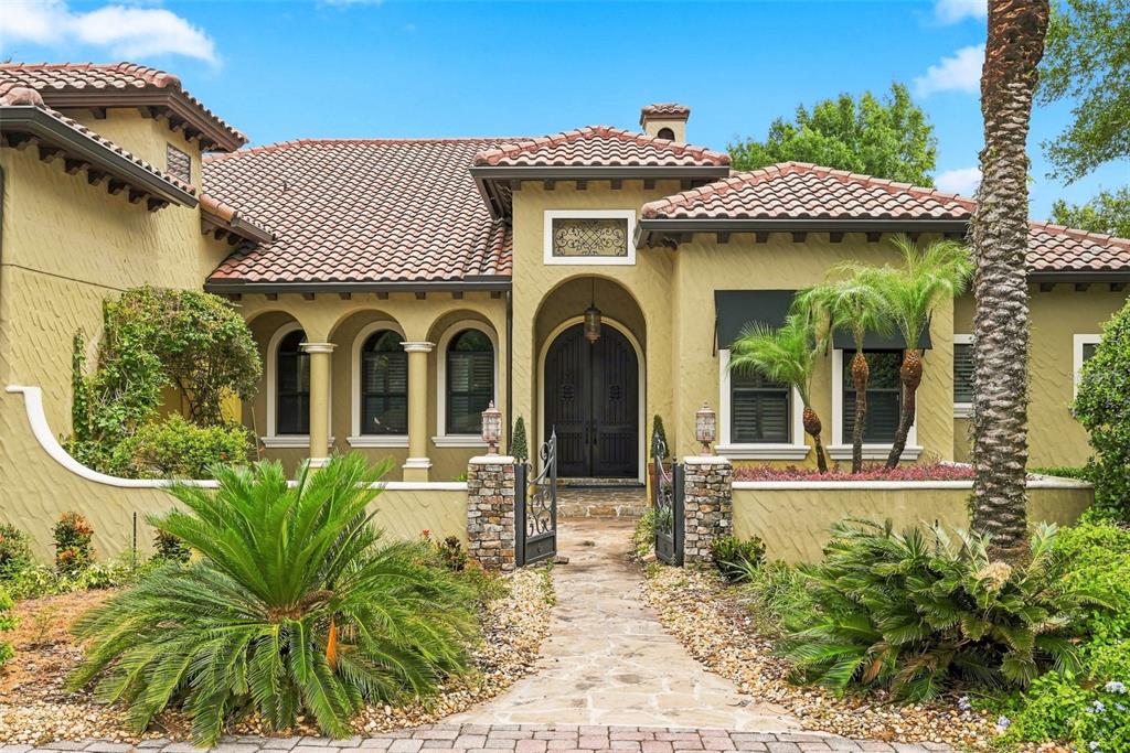 A Mediterranean-style house with a tile roof, arched entryway, and a stone-paved walkway — 9679 WESTOVER ROBERTS RD, WINDERMERE, FL
