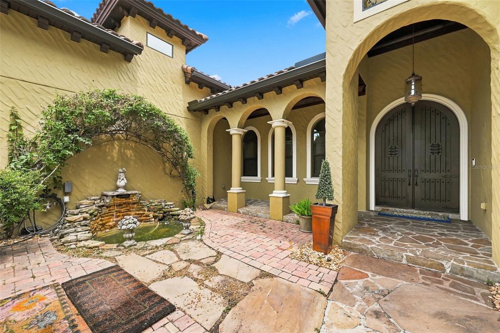 An exterior courtyard features a stone fountain, arched columns, and a double-door entryway — 9679 WESTOVER ROBERTS RD, WINDERMERE, FL