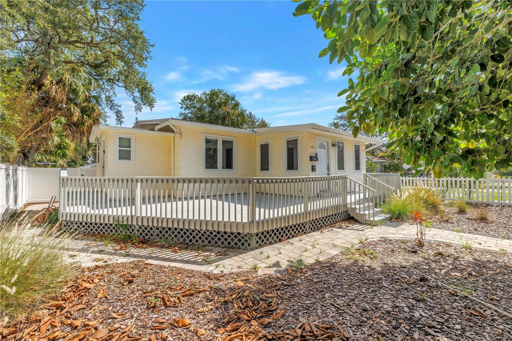 A light yellow house features a large wooden deck and a paver walkway — 109 20TH AVENUE S, ST PETERSBURG, FL