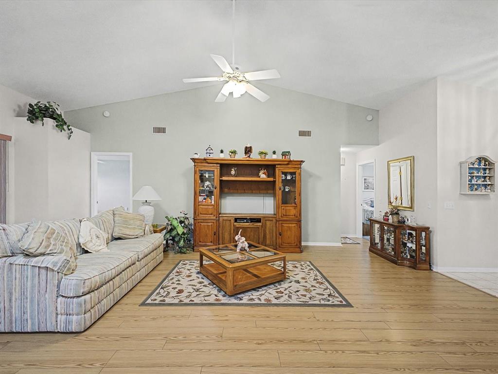 A living room features light wood flooring, a vaulted ceiling, and a wooden entertainment center — 11625 BARONWOOD COURT, HUDSON, FL