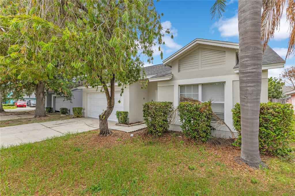 A single-story house with a beige exterior, a two-car garage, and a front yard — 8821 PARLIAMENT COURT, KISSIMMEE, FL