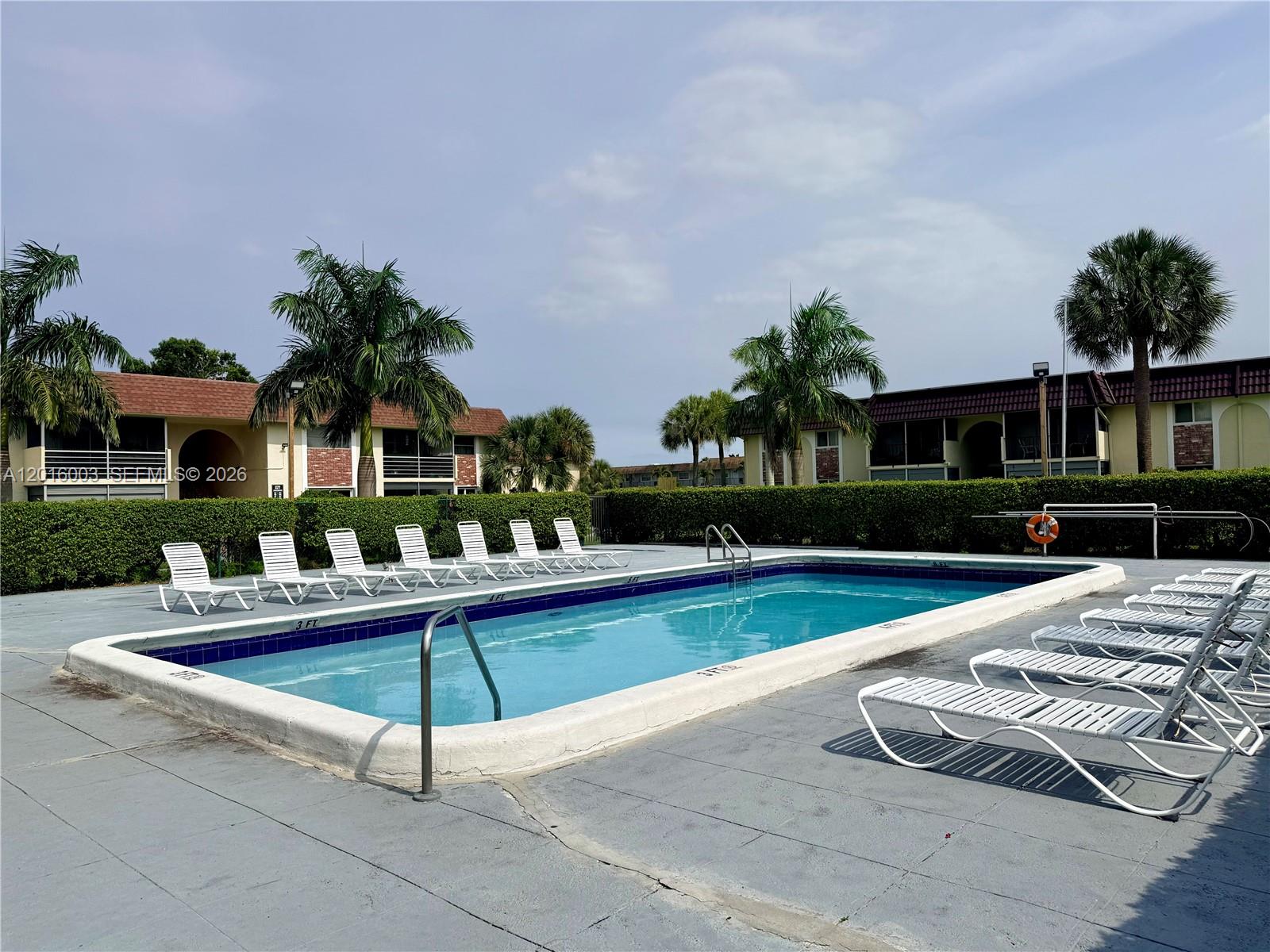 A rectangular swimming pool is surrounded by a concrete deck and lounge chairs — 22805 SW 66th Ave # 208, Boca Raton FL 33428, BOCA RATON, FL