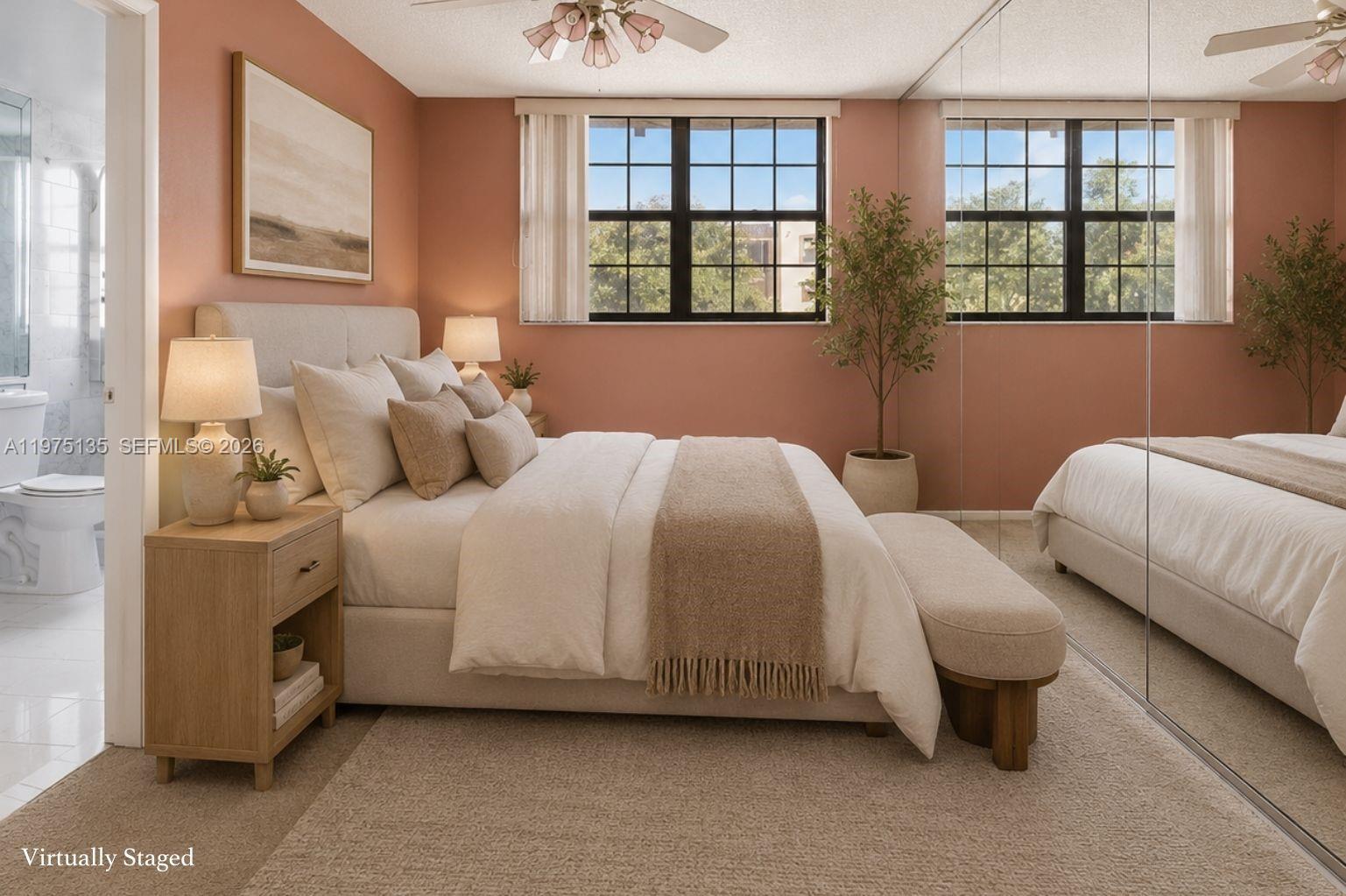A bedroom with terracotta walls, a beige upholstered bed, and mirrored closet doors — 12253 SW 16th Ter # M, Miami FL 33175, MIAMI, FL