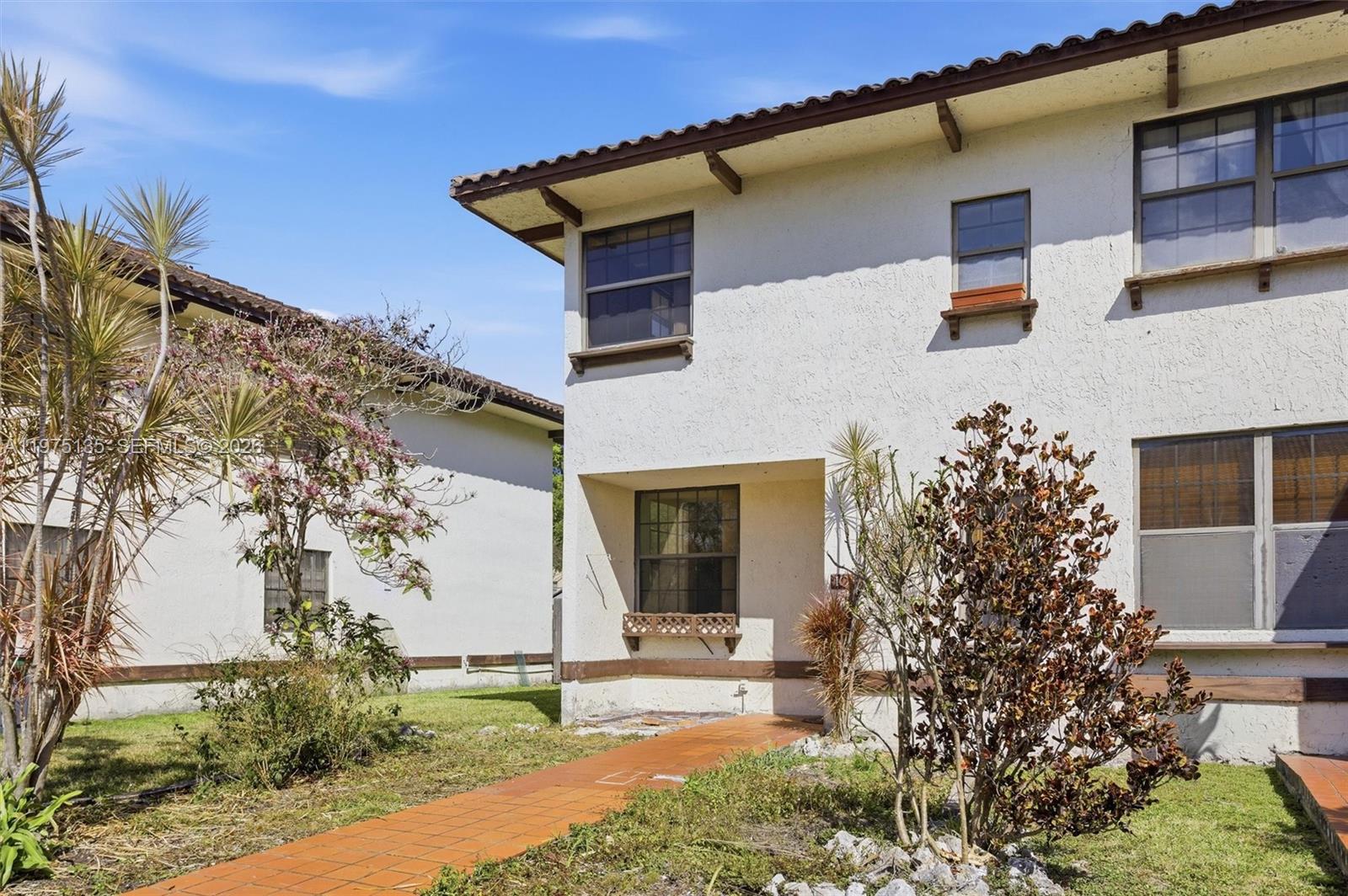 A two-story stucco building with a tiled roof and a brick walkway leading to entrance — 12253 SW 16th Ter # M, Miami FL 33175, MIAMI, FL