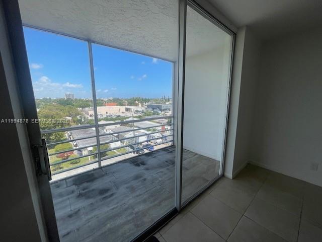 A balcony with tiled flooring and a metal railing overlooks a suburban neighborhood — 1830 Dixieanna St # 606, Hollywood FL 33020, HOLLYWOOD, FL