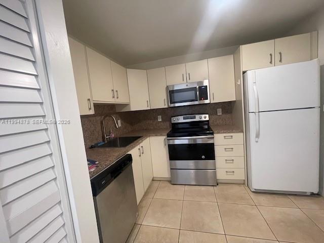 A kitchen features light-colored cabinets, stainless steel appliances, and tile flooring — 1830 Dixieanna St # 606, Hollywood FL 33020, HOLLYWOOD, FL