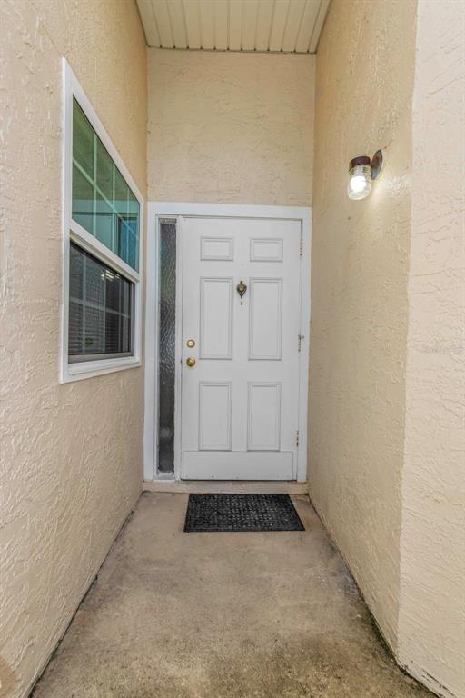 A white front door with a sidelight and a small window sits in a recessed entryway — 3199 PHLOX DRIVE UNIT 214, PALM HARBOR, FL