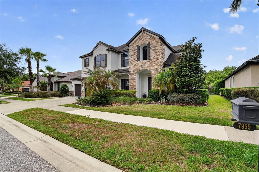 A two-story house with a stone facade, stucco exterior, and a front-facing mailbox — 7959 HAMPTON LAKE DRIVE, TAMPA, FL