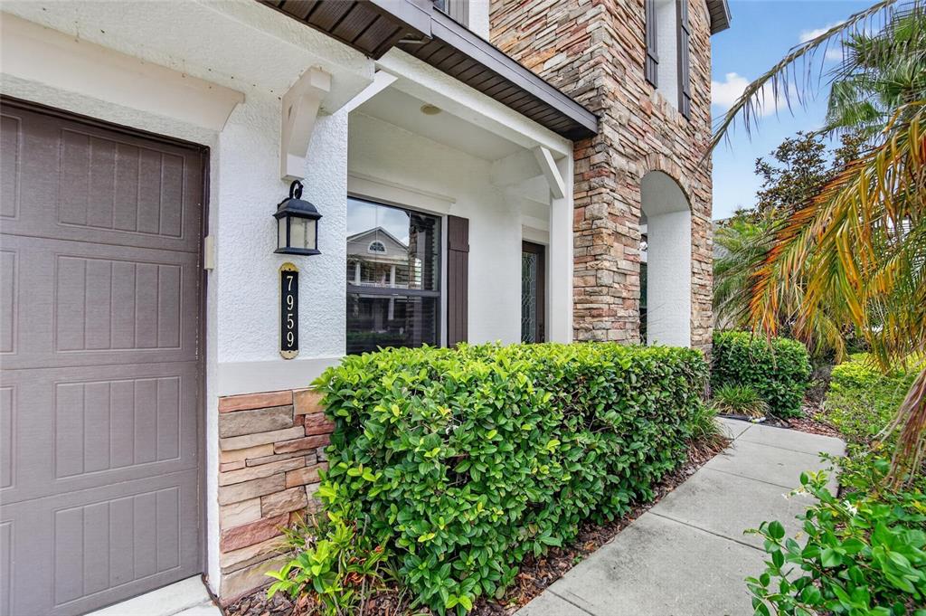 The exterior of a house features a garage, stone accents, a hedge, and a walkway — 7959 HAMPTON LAKE DRIVE, TAMPA, FL