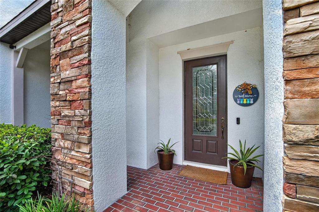 A front entryway features a brown door, brick flooring, and stone pillars on both sides — 7959 HAMPTON LAKE DRIVE, TAMPA, FL