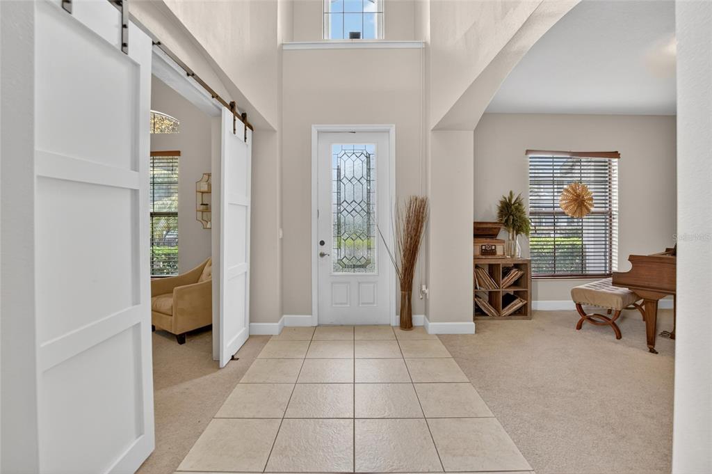 An entryway with tile flooring, a white front door, and sliding barn doors — 7959 HAMPTON LAKE DRIVE, TAMPA, FL