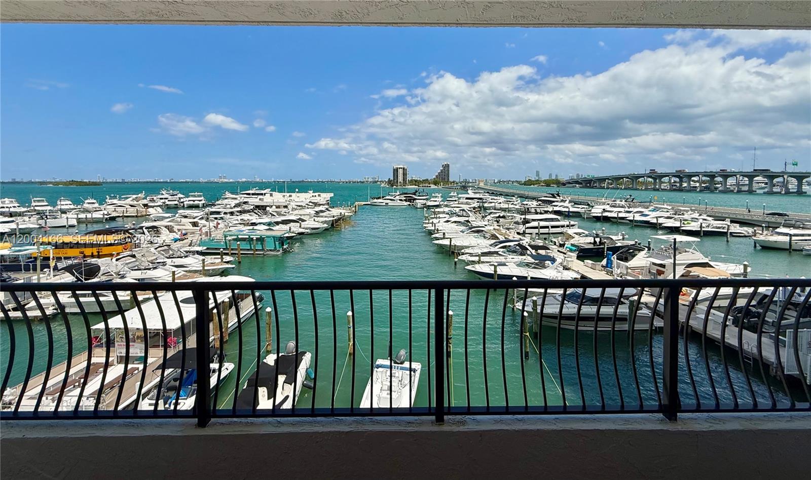 A balcony view overlooks a marina filled with numerous boats under a partly cloudy sky — 555 NE 15th St # 420, Miami FL 33132, MIAMI, FL