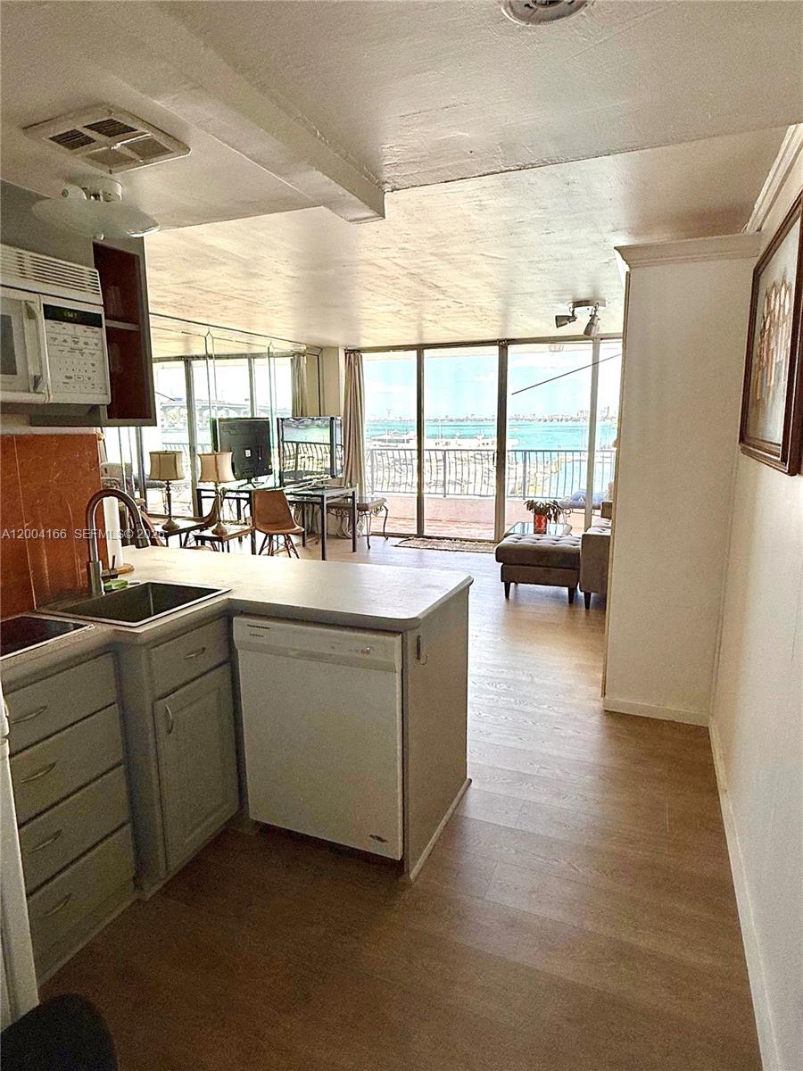 A kitchen with gray cabinets and a dishwasher overlooks a living area with water views — 555 NE 15th St # 420, Miami FL 33132, MIAMI, FL