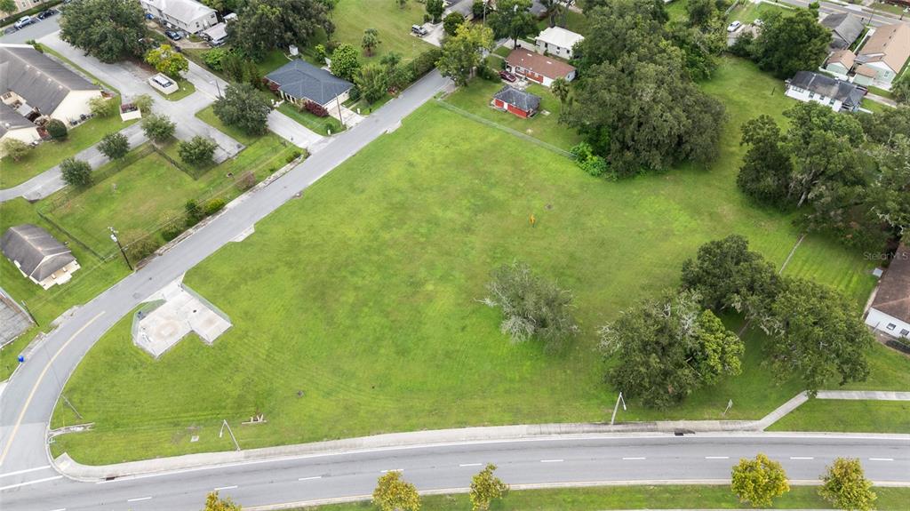 An aerial view shows a large, grassy vacant lot bordered by roads and residential houses — KATHLEEN ROAD, LAKELAND, FL