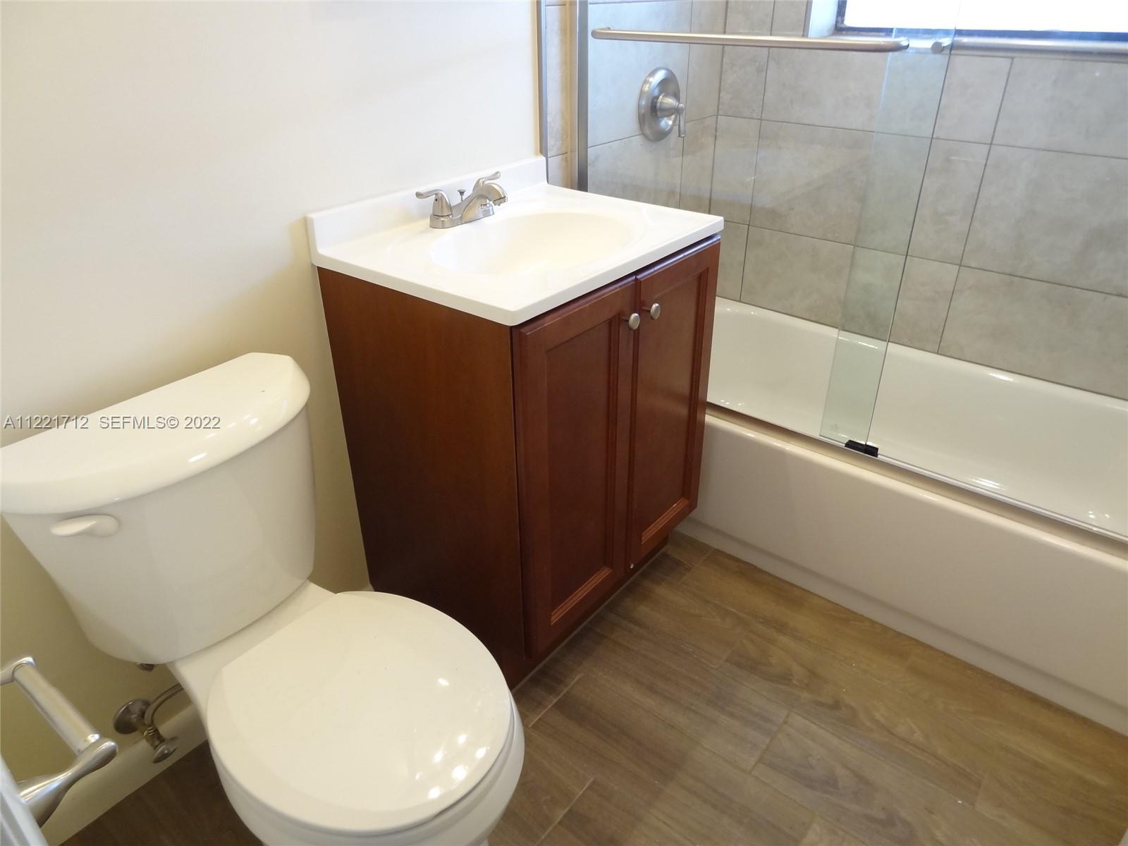 A bathroom features a white toilet, a wood vanity with a sink, and a bathtub — 2212 Johnson St, Hollywood FL 33020, HOLLYWOOD, FL