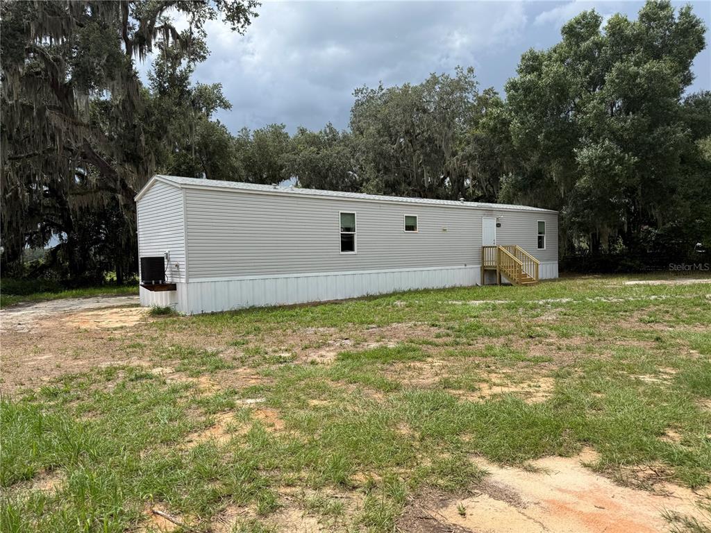 A single-story manufactured home with light gray siding sits on a grassy lot — 5642 MEADOW GLEN ROAD, LAKELAND, FL