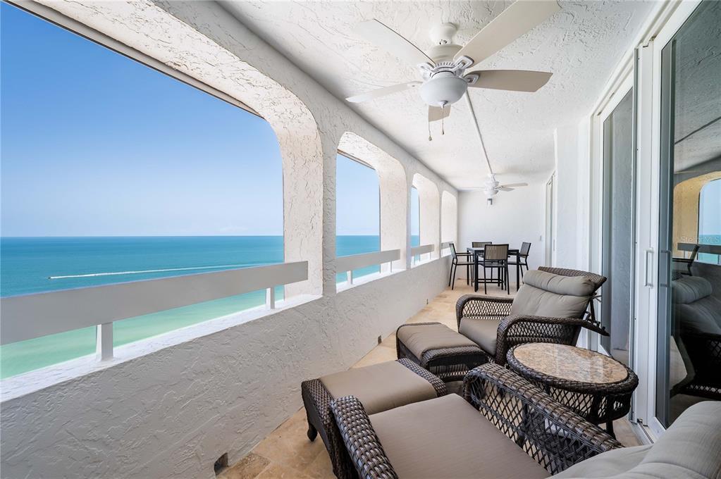 A balcony with wicker furniture and a ceiling fan overlooks the ocean — 17940 GULF BOULEVARD UNIT 18C, REDINGTON SHORES, FL