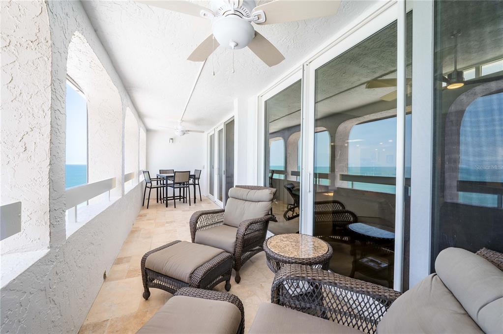 A balcony with tile flooring, wicker furniture, ceiling fans, and views of the ocean — 17940 GULF BOULEVARD UNIT 18C, REDINGTON SHORES, FL