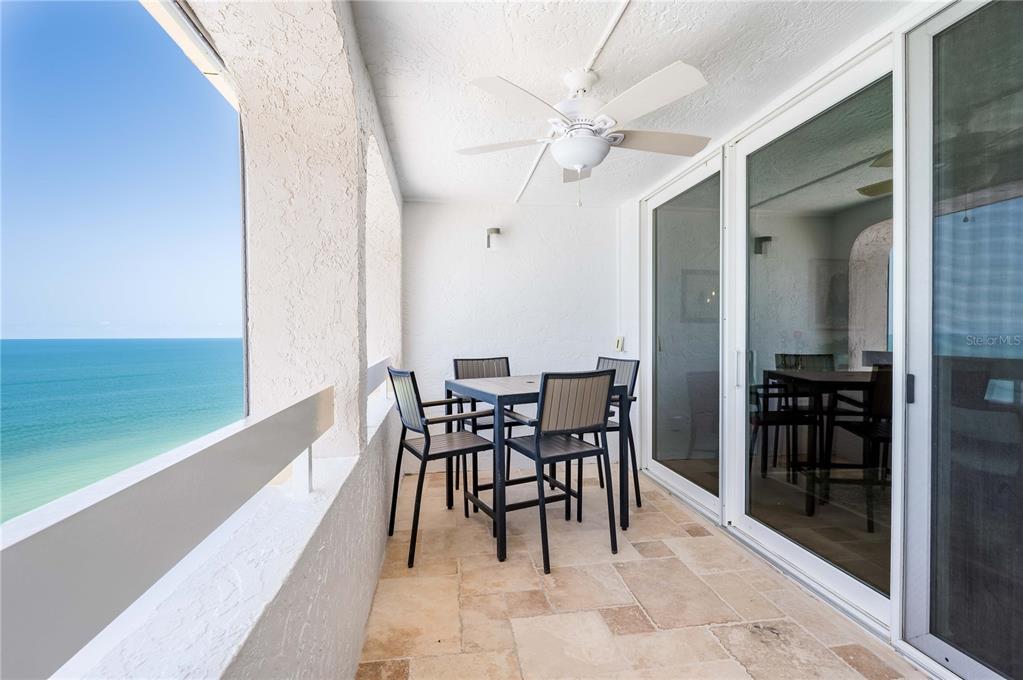 A balcony with a dining set, ceiling fan, stone flooring, and ocean views — 17940 GULF BOULEVARD UNIT 18C, REDINGTON SHORES, FL