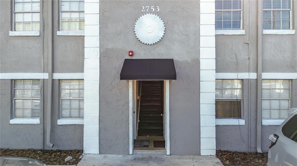 The exterior of a multi-story apartment building features a central entrance with a black awning — 2753 L B MCLEOD ROAD UNIT D, ORLANDO, FL