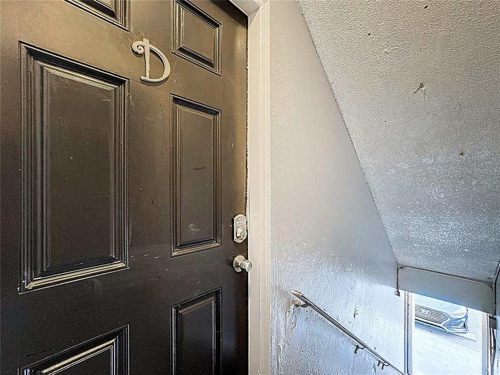 A black door marked with the letter D is positioned next to a stairwell — 2753 L B MCLEOD ROAD UNIT D, ORLANDO, FL