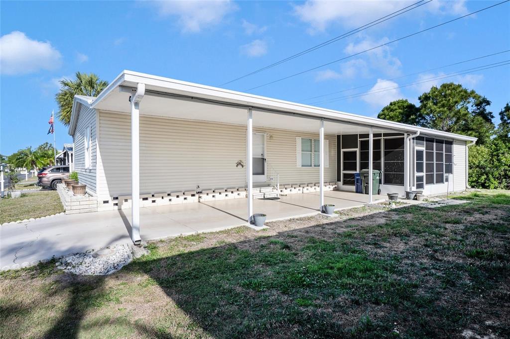 A single-story mobile home features a large covered carport and an attached screened-in porch — 2165 GONDOLA DRIVE, SARASOTA, FL