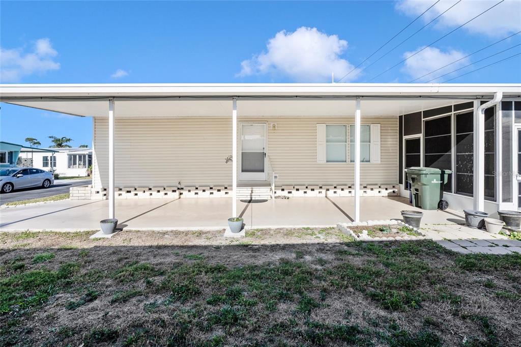A covered concrete patio extends along the front of a light-colored mobile home — 2165 GONDOLA DRIVE, SARASOTA, FL