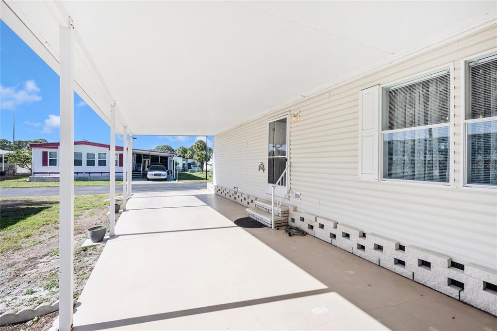 A covered concrete carport and porch area runs alongside the side of a mobile home — 2165 GONDOLA DRIVE, SARASOTA, FL