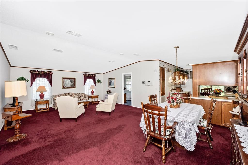A living and dining area with deep red carpeting, vaulted ceilings, and wooden furniture — 2165 GONDOLA DRIVE, SARASOTA, FL