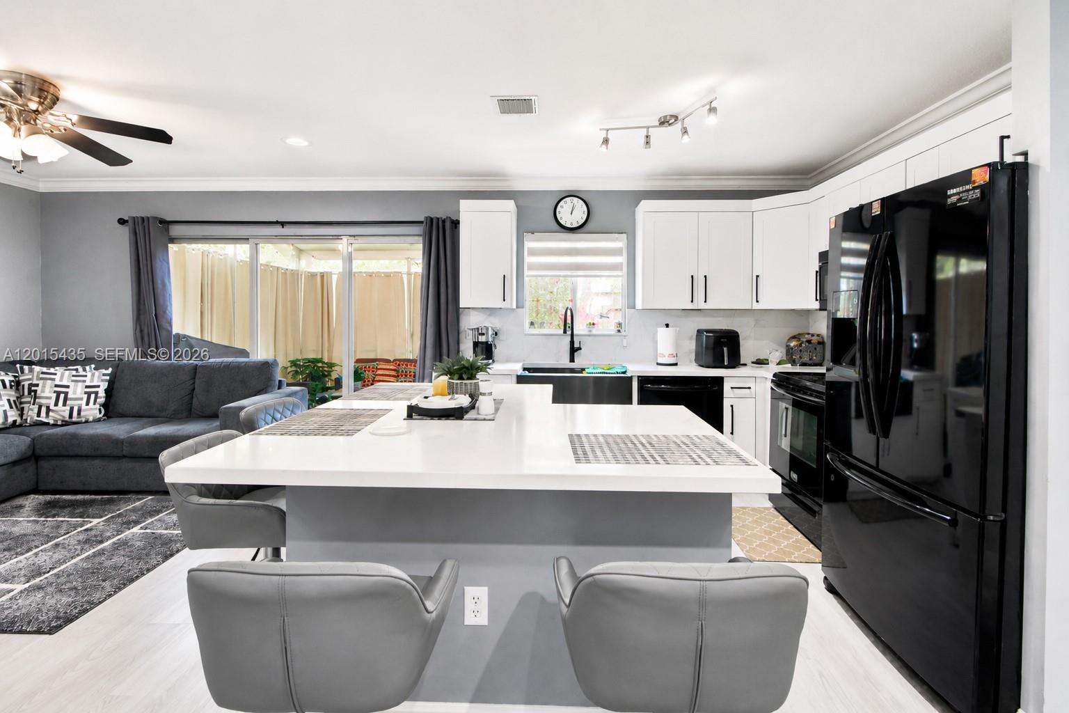 A modern kitchen features white cabinets, a large quartz island, and black appliances — 4946 SW 66th Ter, Davie FL 33314, DAVIE, FL