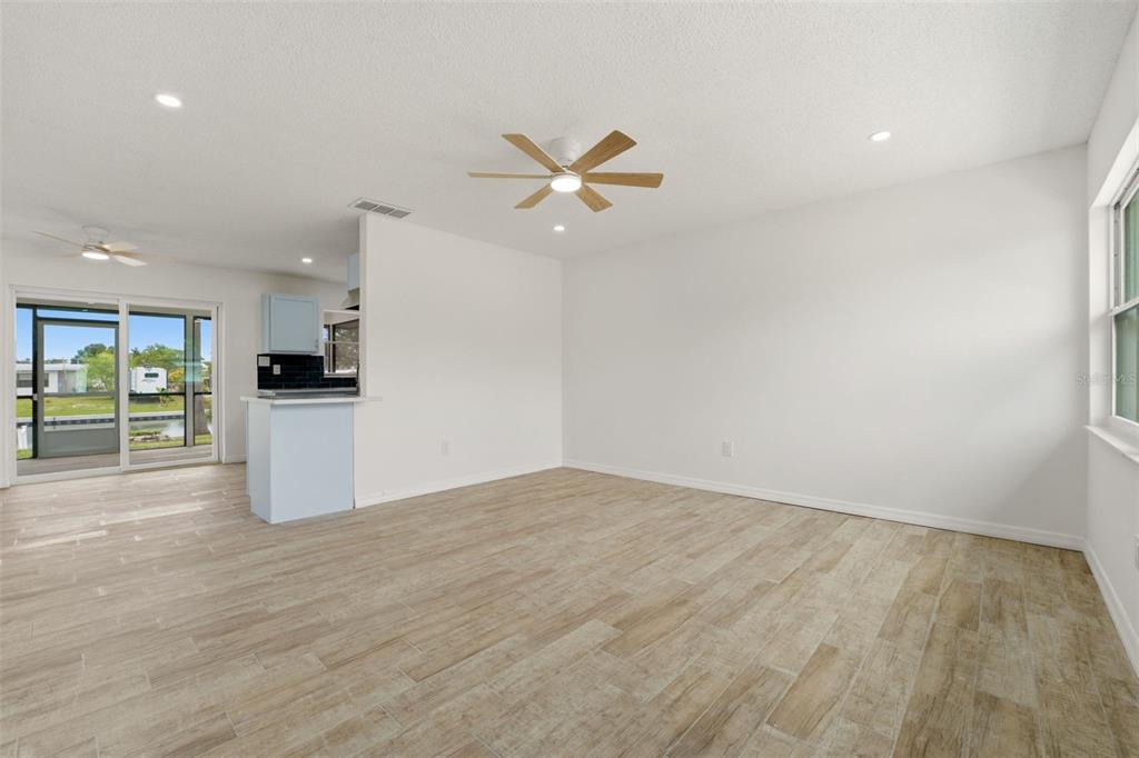 A bright living area with light wood-look tile flooring, a ceiling fan, and sliding doors — 178 DOWLING AVENUE NE, PORT CHARLOTTE, FL