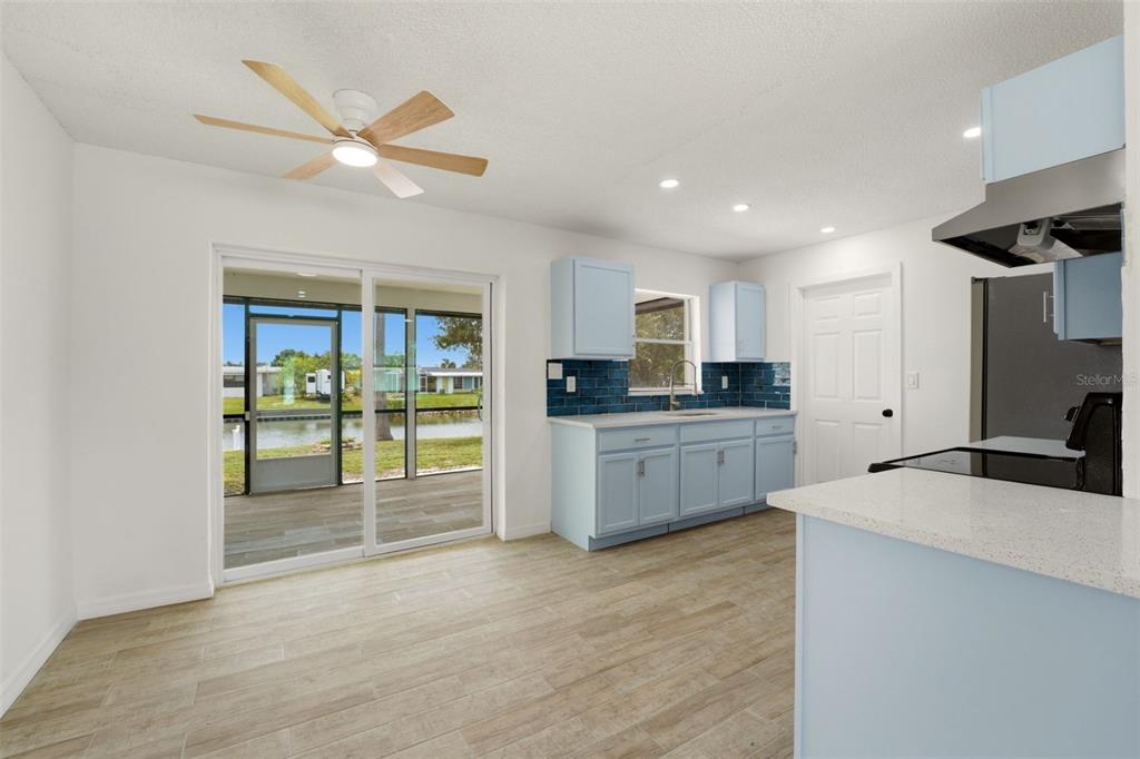 A kitchen with light blue cabinets, a dark blue backsplash, and a sliding glass door — 178 DOWLING AVENUE NE, PORT CHARLOTTE, FL