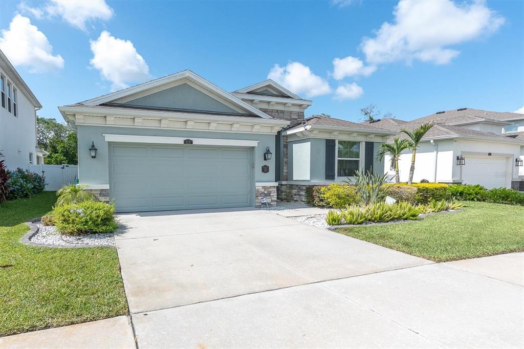 A light blue single-story house with a two-car garage and stone accents — 8110 PRAISE DRIVE, TAMPA, FL