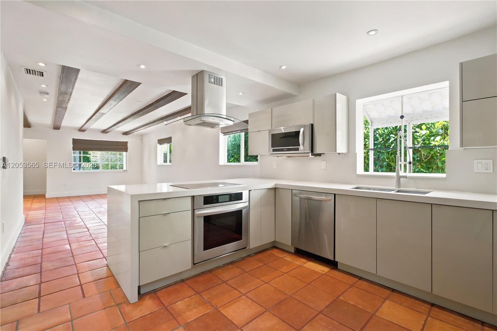A modern kitchen features light gray cabinetry, stainless steel appliances, and terracotta tile flooring — 3945 SW 61st Ave, Miami FL 33155, MIAMI, FL