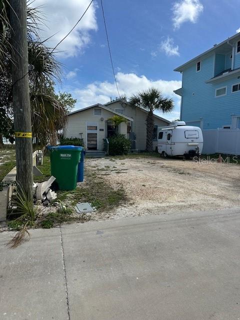 A small, light-colored house with a gravel driveway and a parked camper trailer — 12620 LAGOON LANE, TREASURE ISLAND, FL