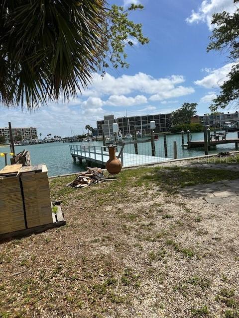 A view of a wooden dock extending into a canal with buildings in the background — 12620 LAGOON LANE, TREASURE ISLAND, FL