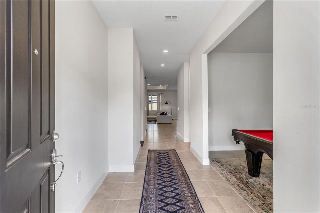 A tiled entryway leads to a hallway with a runner rug and a pool table — 3980 MEANDERING BAY DRIVE, APOPKA, FL